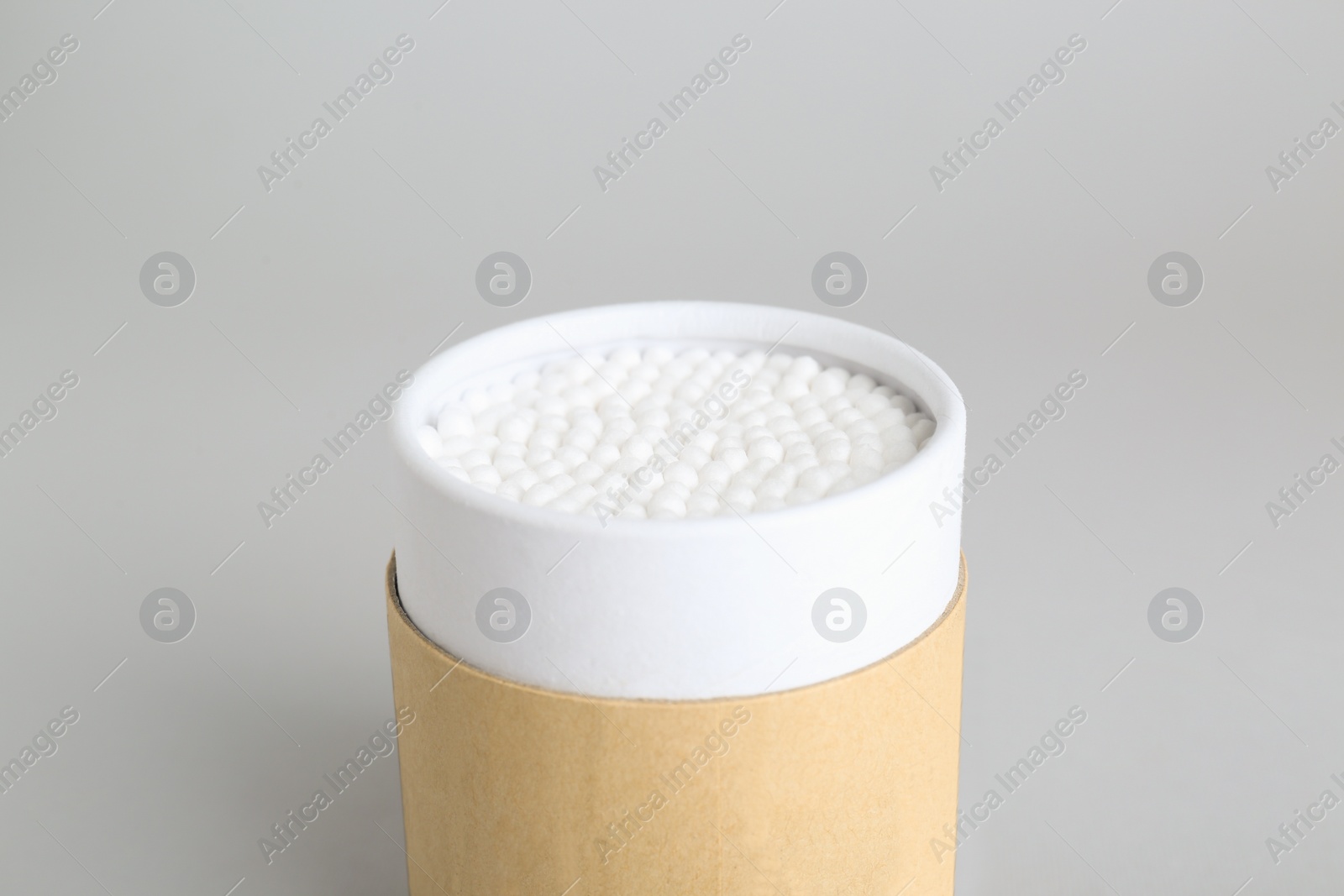 Photo of Container with new cotton buds on light grey background, closeup