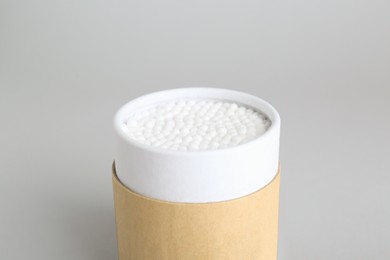 Container with new cotton buds on light grey background, closeup