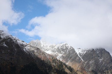 Picturesque view of high mountains under cloudy sky