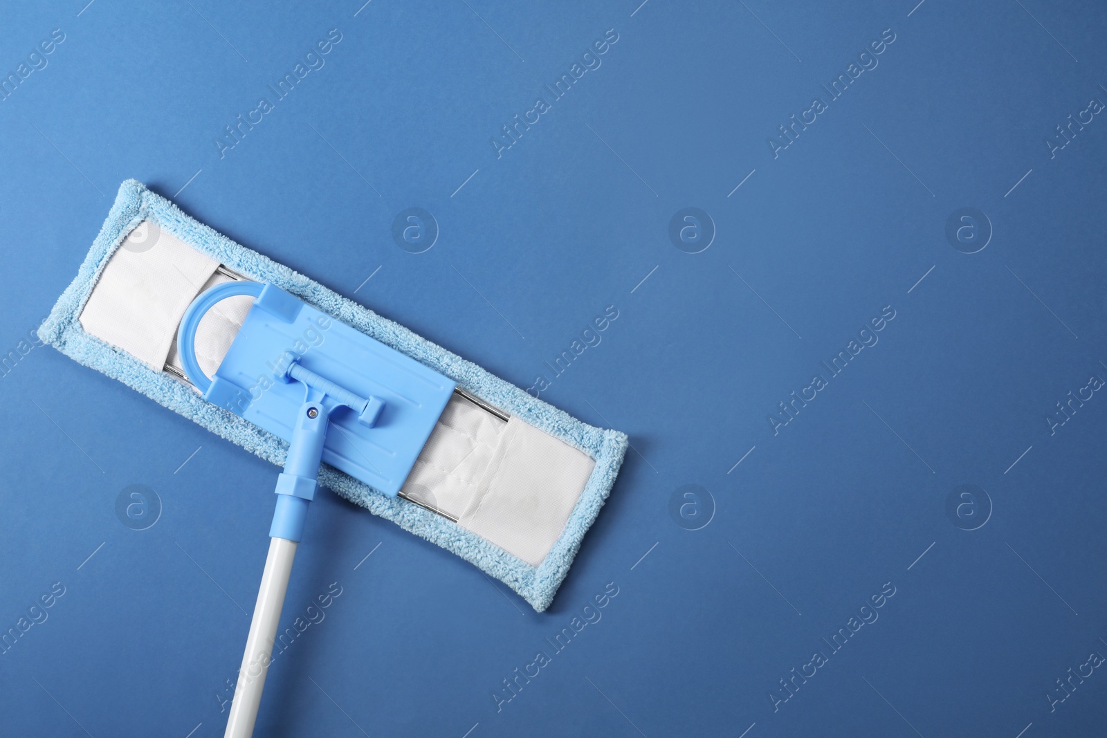 Photo of Mop with plastic handle on blue background, top view. Space for text