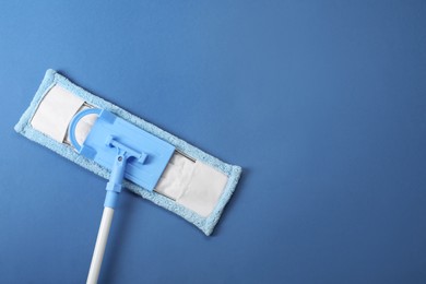 Mop with plastic handle on blue background, top view. Space for text