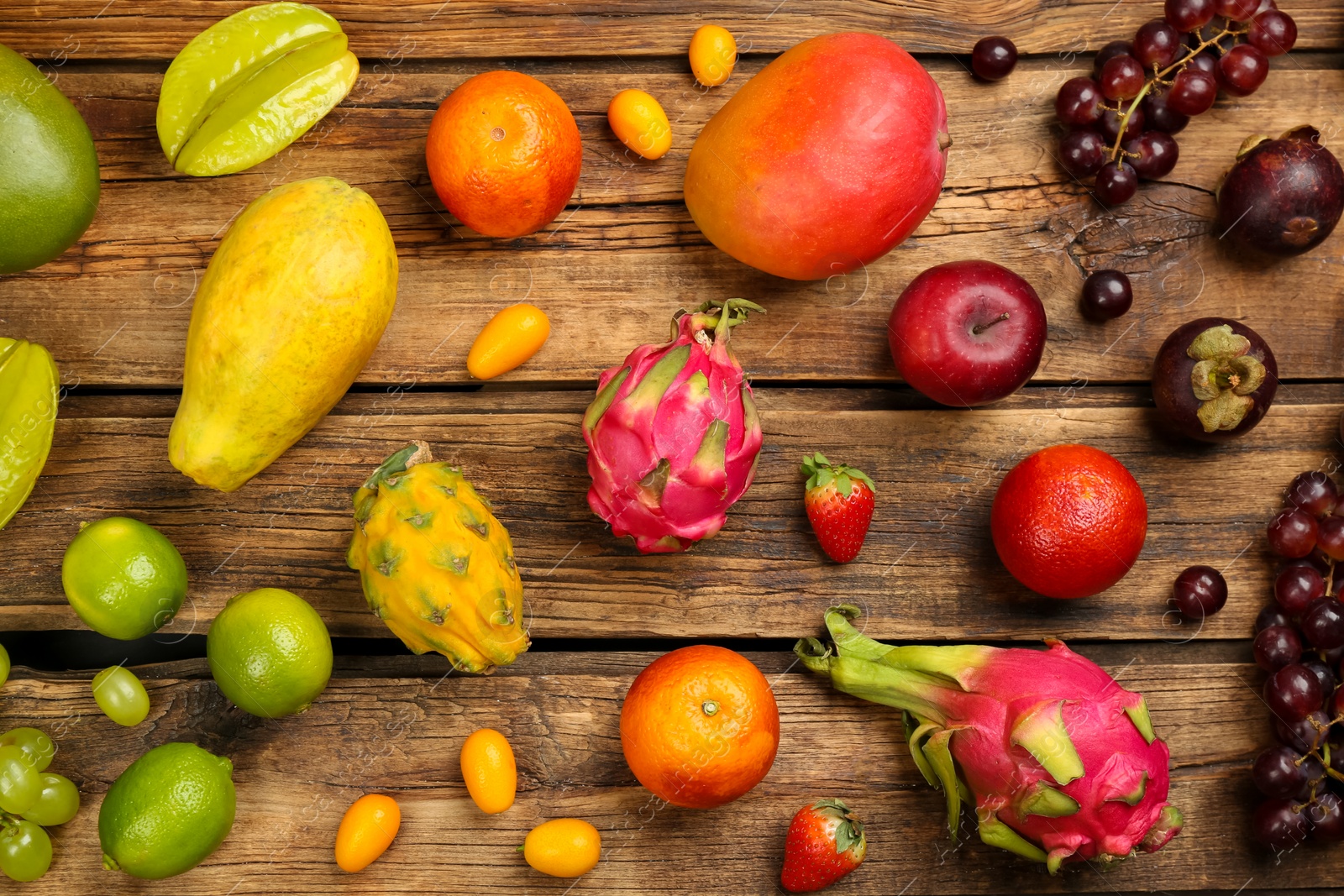 Photo of Many different delicious exotic fruits on wooden table, flat lay