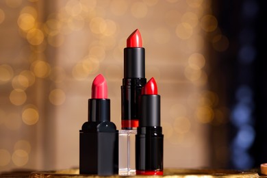 Photo of Beautiful red and pink lipsticks against blurred lights