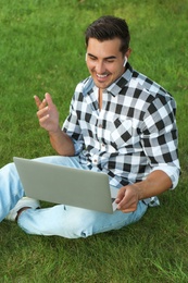 Portrait of young man with laptop outdoors