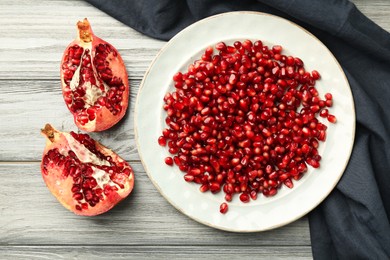 Photo of Tasty ripe pomegranate and grains on light wooden table, flat lay