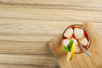 Photo of Glass of tasty ice tea with lemon on wooden table, top view. Space for text