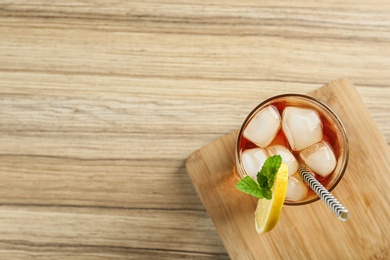 Glass of tasty ice tea with lemon on wooden table, top view. Space for text