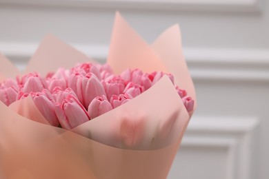 Photo of Bouquet of beautiful pink tulips near white wall, closeup. Space for text