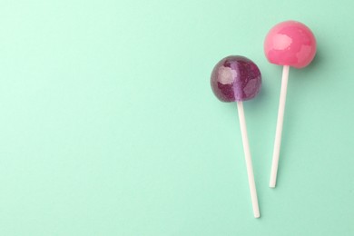 Photo of Tasty lollipops on turquoise background, flat lay. Space for text