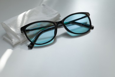 Stylish black eye glasses and cloth on white table. Space for text