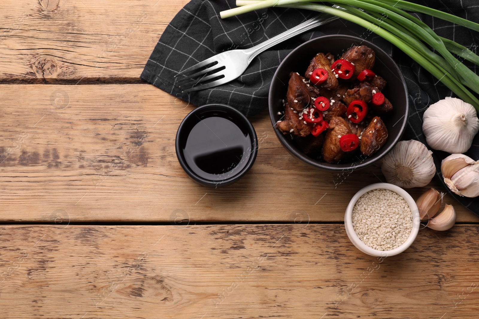 Photo of Tasty roasted meat, soy sauce and products on wooden table, flat lay. Space for text