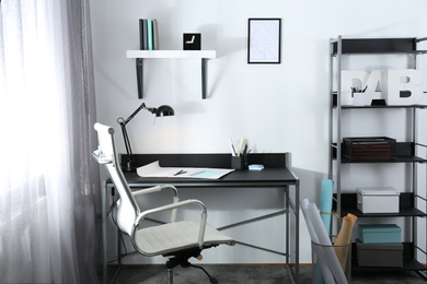 Photo of Stylish room interior with comfortable workplace near window. Design idea