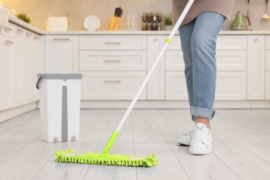 Photo of Woman cleaning floor with mop indoors, closeup