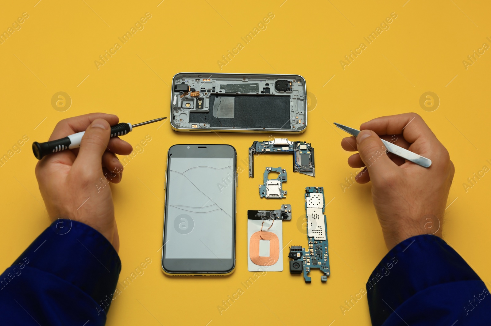 Photo of Man repairing broken smartphone on yellow background, above view