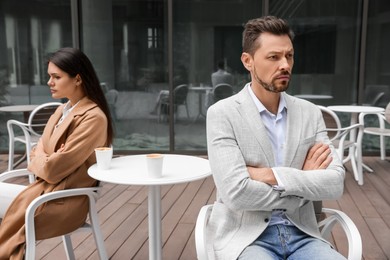 Photo of Upset arguing couple in outdoor cafe. Relationship problems