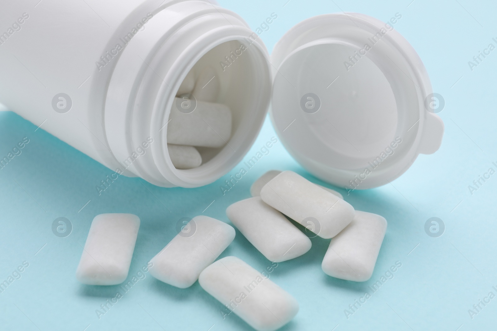 Photo of Jar with chewing gums on light blue background, closeup