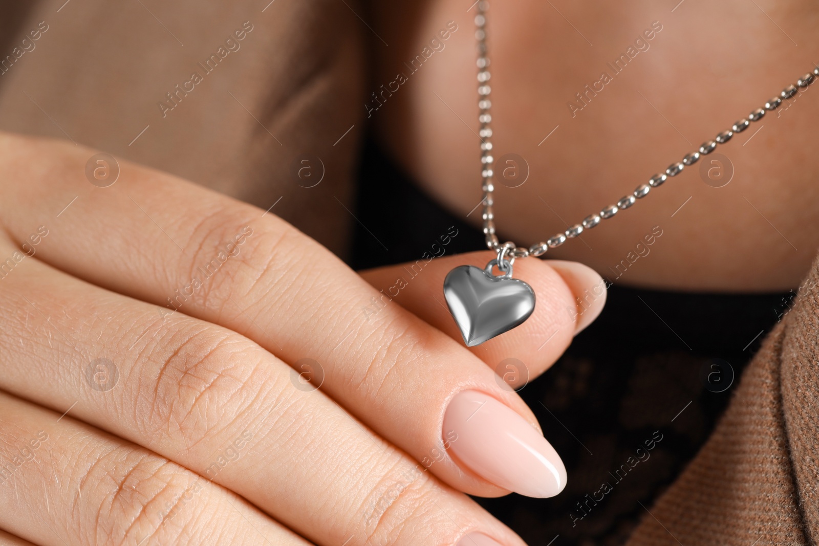 Photo of Woman wearing stylish metal chain with pendant, closeup. Luxury jewelry