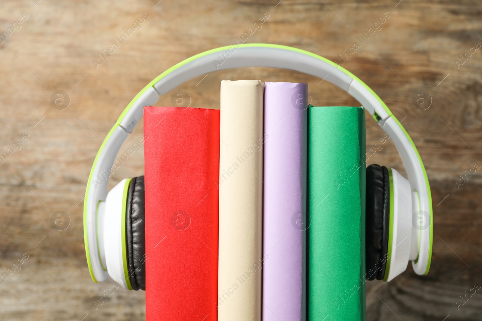 Photo of Books and modern headphones on wooden background, closeup