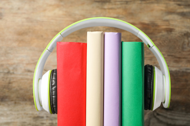 Books and modern headphones on wooden background, closeup