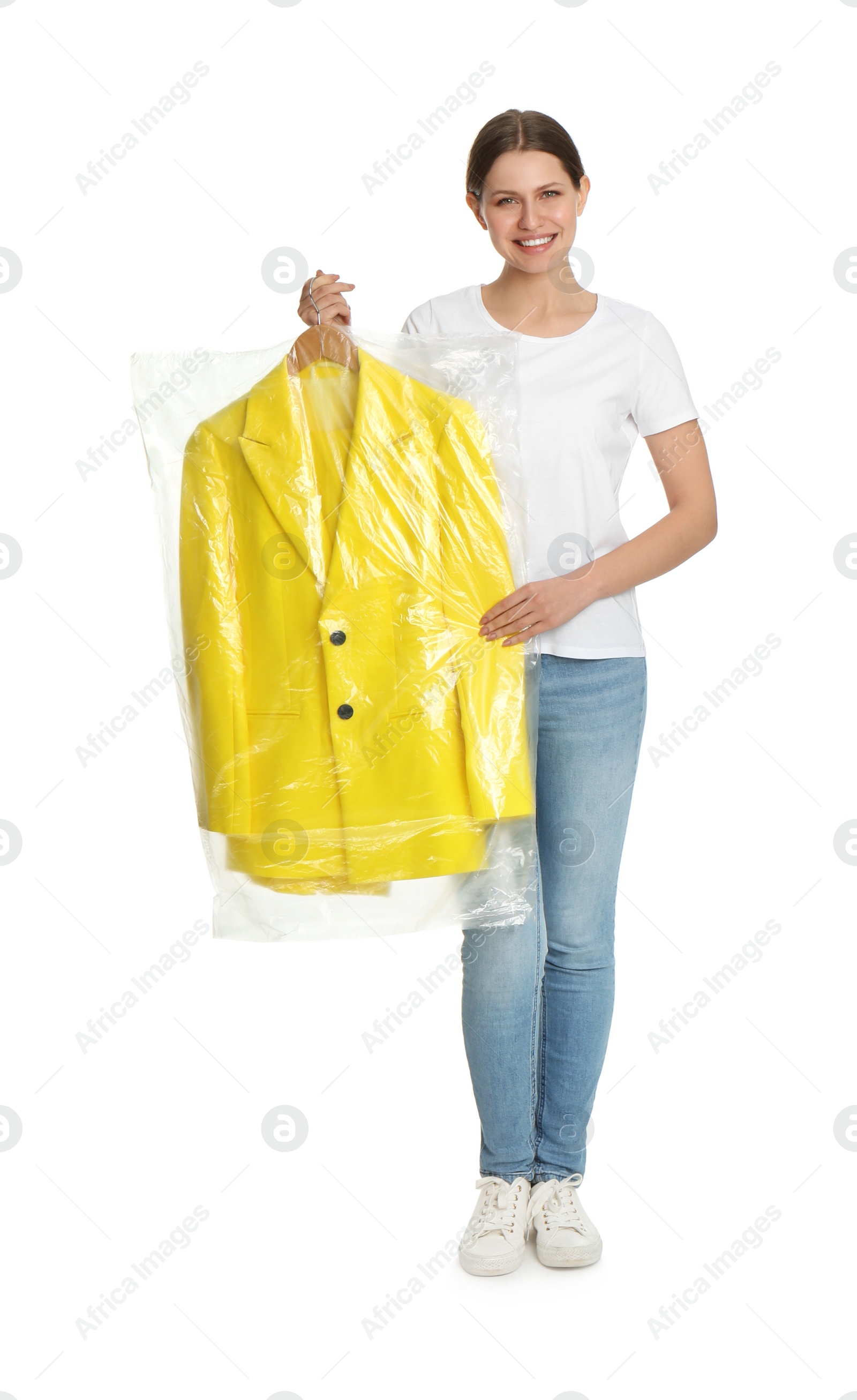 Photo of Young woman holding hanger with jacket in plastic bag on white background. Dry-cleaning service