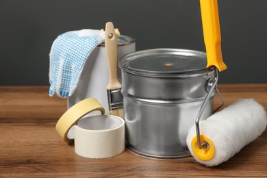 Photo of Cans of orange paint and renovation equipment on wooden table