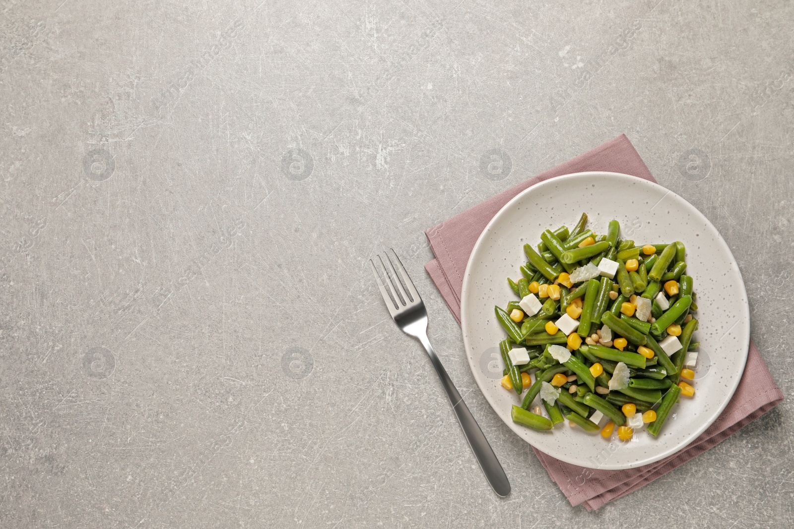 Photo of Delicious salad with green beans, corn and cheese served on light table, flat lay. Space for text