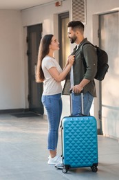 Photo of Long-distance relationship. Beautiful young couple with luggage near house entrance outdoors