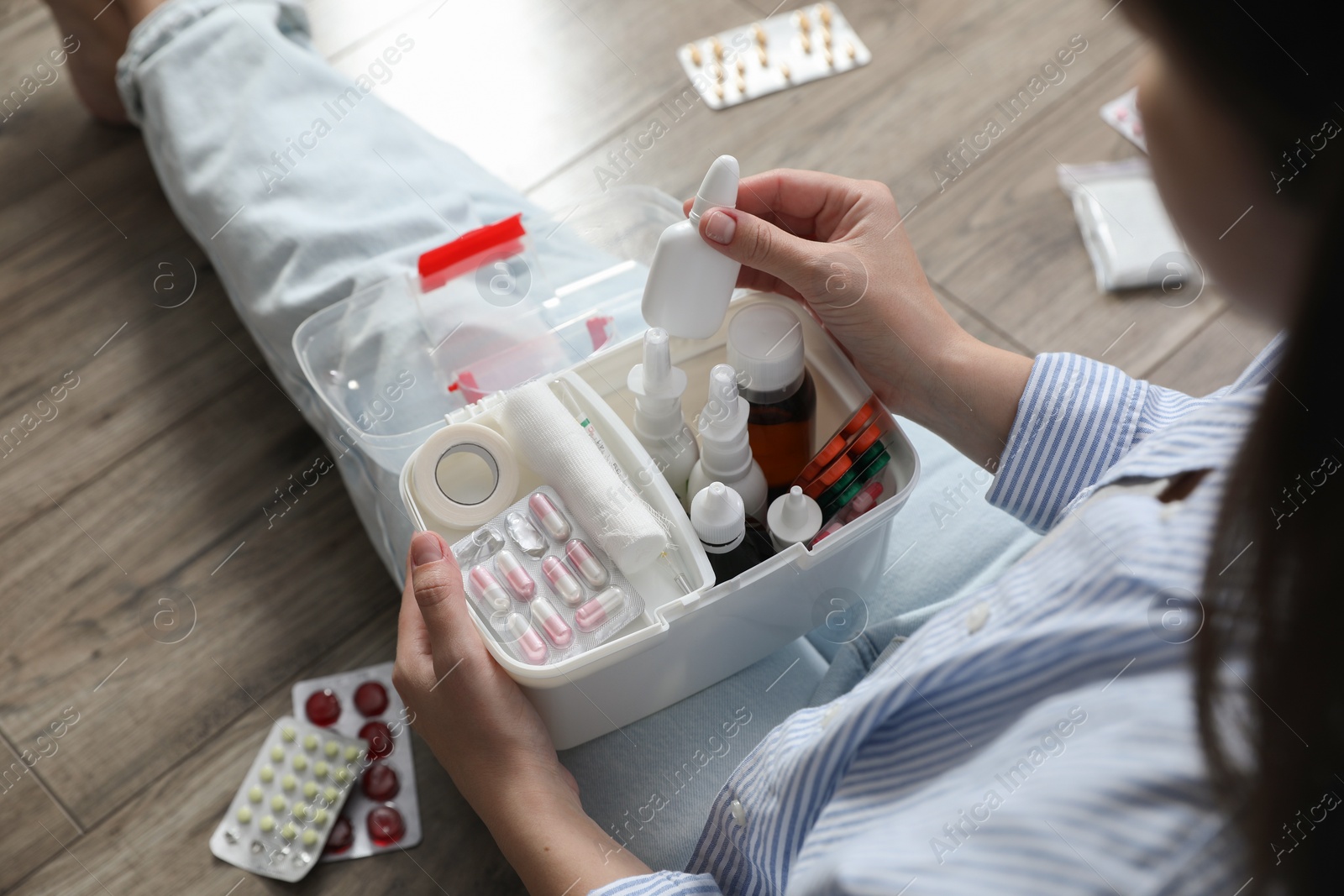 Photo of Woman putting medicament into first aid kit indoors, above view