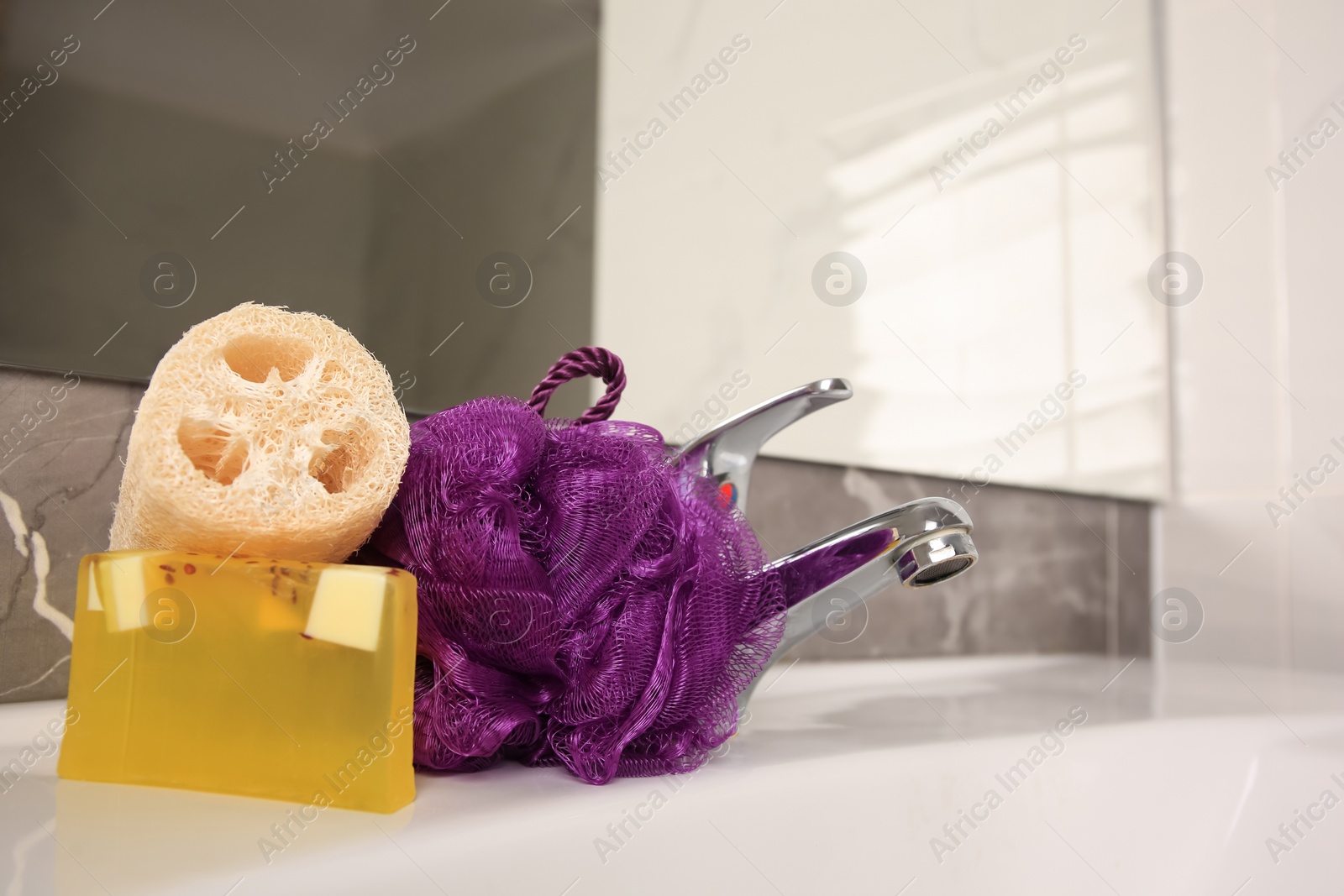 Photo of Purple shower puff, loofah sponge and soap on sink in bathroom, space for text