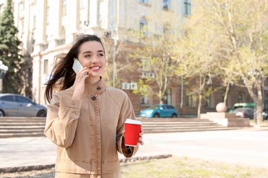 Photo of Young woman talking by phone outdoors on sunny day