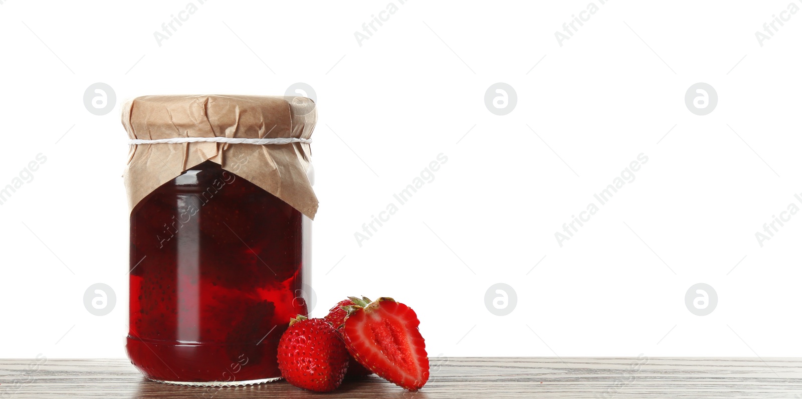 Photo of Glass jar of pickled strawberries on wooden table against white background. Space for text