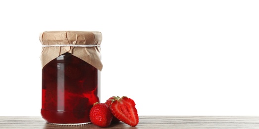 Photo of Glass jar of pickled strawberries on wooden table against white background. Space for text