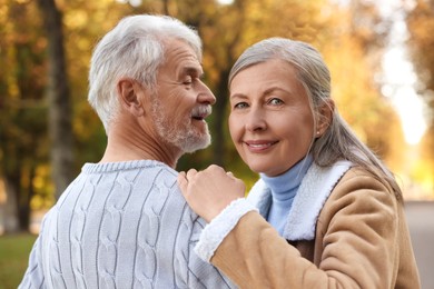 Affectionate senior couple dancing together in autumn park