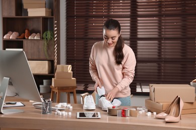 Photo of Seller packing shoes at workplace. Online store