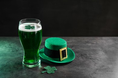 Photo of St. Patrick's day celebration. Green beer, leprechaun hat and decorative clover leaves on grey table. Space for text