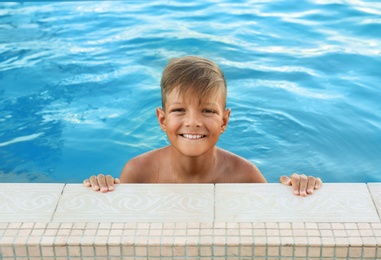 Happy cute boy in swimming pool on sunny day