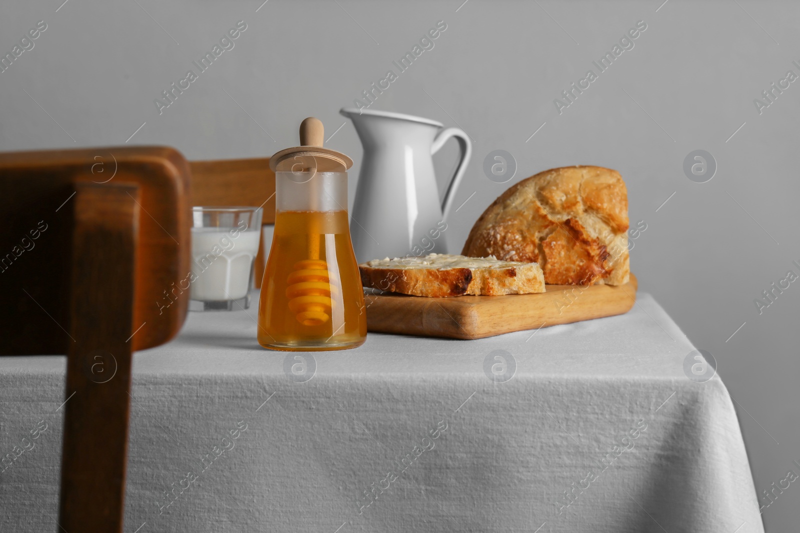 Photo of Delicious honey, milk and bread with butter served for breakfast on table indoors