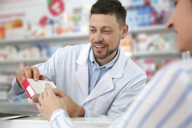 Photo of Professional pharmacist giving medicine to customer in drugstore