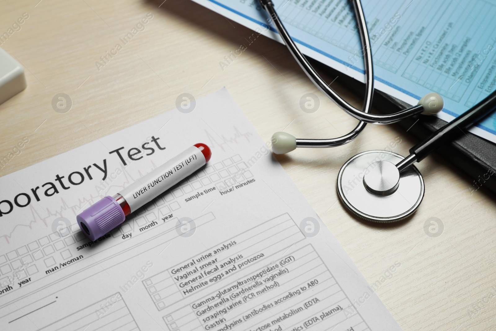 Photo of Liver Function Test. Tube with blood sample, stethoscope and laboratory forms on wooden table