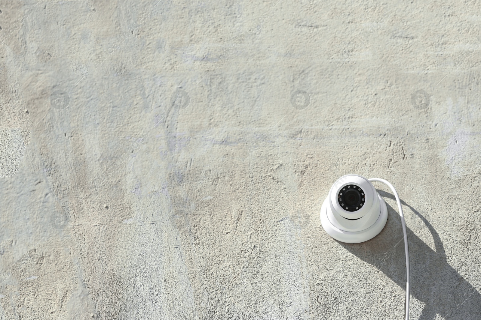 Photo of Modern CCTV security camera on stone building wall outdoors. Space for text