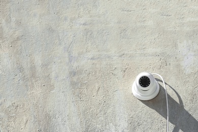 Photo of Modern CCTV security camera on stone building wall outdoors. Space for text