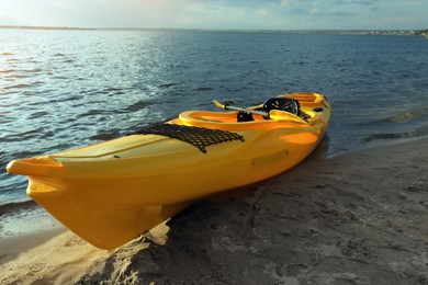 Beautiful modern yellow kayak with paddle on beach