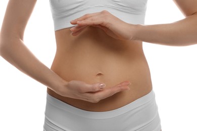 Photo of Woman holding hands near belly against white background, closeup