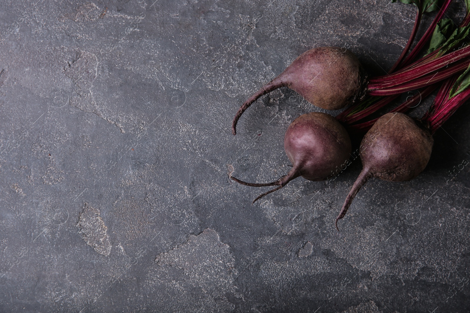 Photo of Fresh beets with leaves on grey table, top view. Space for text