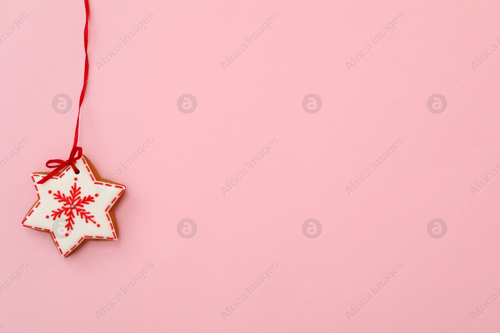 Photo of Snowflake shaped Christmas cookie on pink background, top view. Space for text