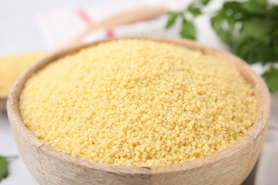 Photo of Raw couscous in wooden bowl on table, closeup