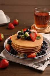 Delicious pancakes with fresh berries and butter served on wooden table