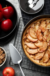 Delicious apple pie and ingredients on grey table, flat lay