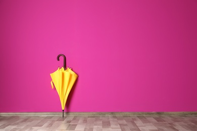 Photo of Beautiful umbrella on floor near color wall with space for design