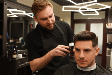 Photo of Professional hairdresser making stylish haircut in salon